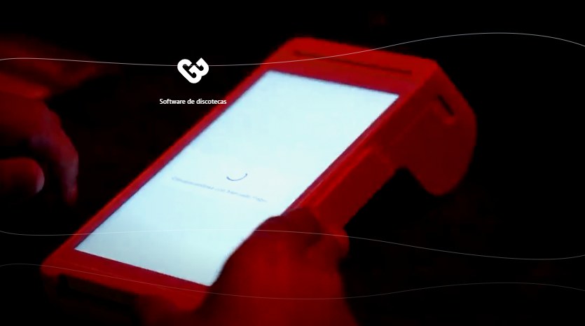 Sistema cashless en una discoteca: terminal POS iluminada en la barra, de noche y con luz roja, mientras el cajero toca la pantalla para cobrar
